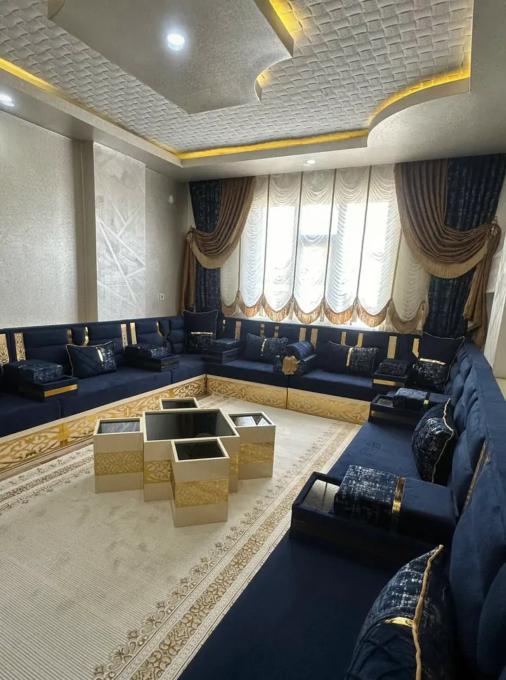 Navy channel-stitched backrests and seats on a cream base with gold arabesque panels, beside box armrests and patterned pillows