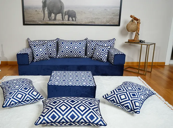 Navy velvet single floor sofa along one wall, with white diamond-pattern back pillows, an ottoman and three floor cushions