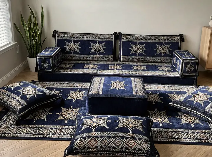 Navy floor sofa with white star motifs, matching backrests and end arms, a square ottoman, loose floor pillows and a patterned rug