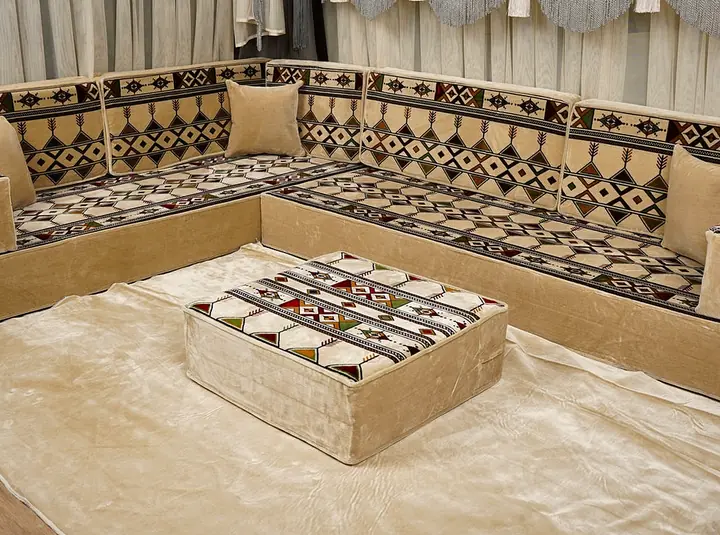 Cream, black and green kilim diamond cushions on an L of floor seating with a pale base and a square ottoman