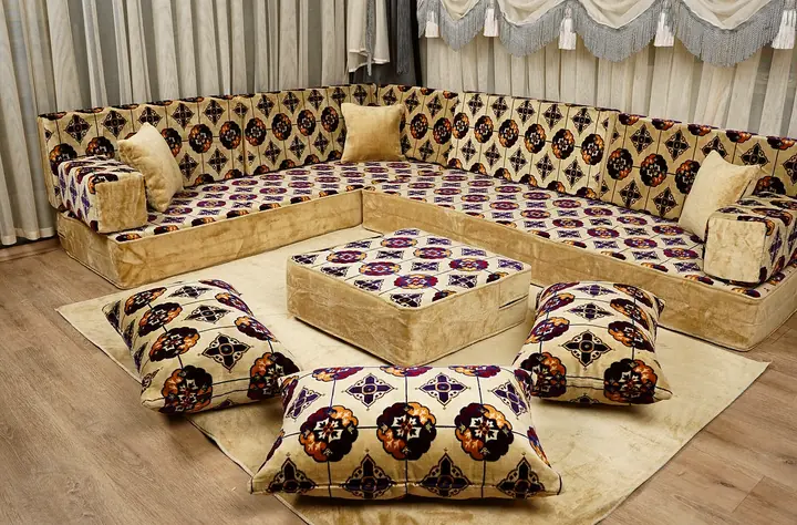 Cream cushions printed with plum and orange rosette medallions on an L of floor seating with three floor pillows