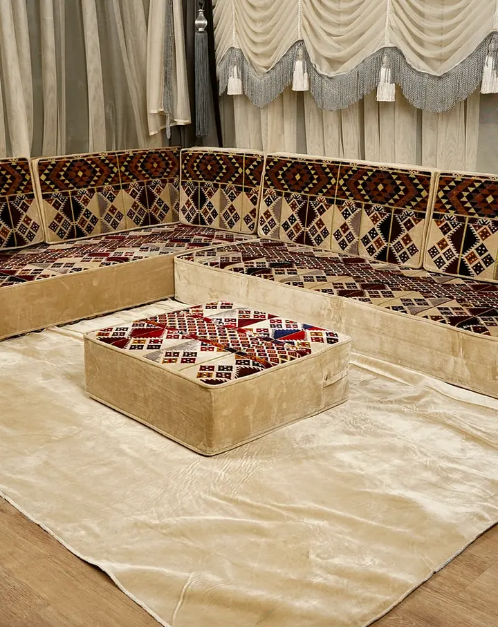 L-shaped floor sofa with a soft cream base and red, brown and navy kilim diamond tops, an ottoman set on a cream rug