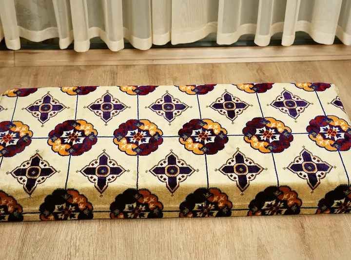 Floor seat cushion with a cream rosette-printed top in plum and orange and beige sides, shown on its own