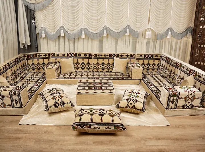 Cream and black kilim diamond floor seating with small green accents on three walls, an ottoman and floor pillows by a carved screen