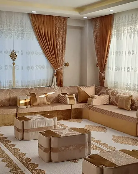 Peach and champagne jacquard majlis along three walls of a bright room, with caramel curtains, embroidered white sheers and cube ottomans