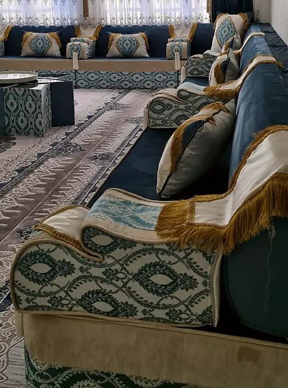 Long run of petrol teal velvet majlis with ogee jacquard armrests, gold fringe trim and matching tables below sheer curtains