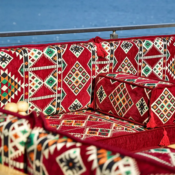 Close view of red kilim backrest cushions and a tasseled bolster on a pine-framed bench seat with turned posts