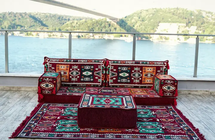 Red kilim-pattern single floor seating set and matching ottoman standing on a red and teal kilim rug on an open terrace