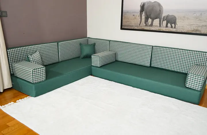 Sage green linen L-shaped floor seating with gingham-check back cushions and bolsters along two walls, no ottoman