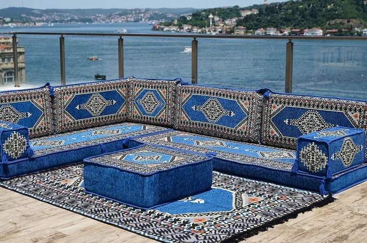 Blue framed-medallion floor couch along two walls, with a medallion-topped blue ottoman resting on a black and white patterned rug