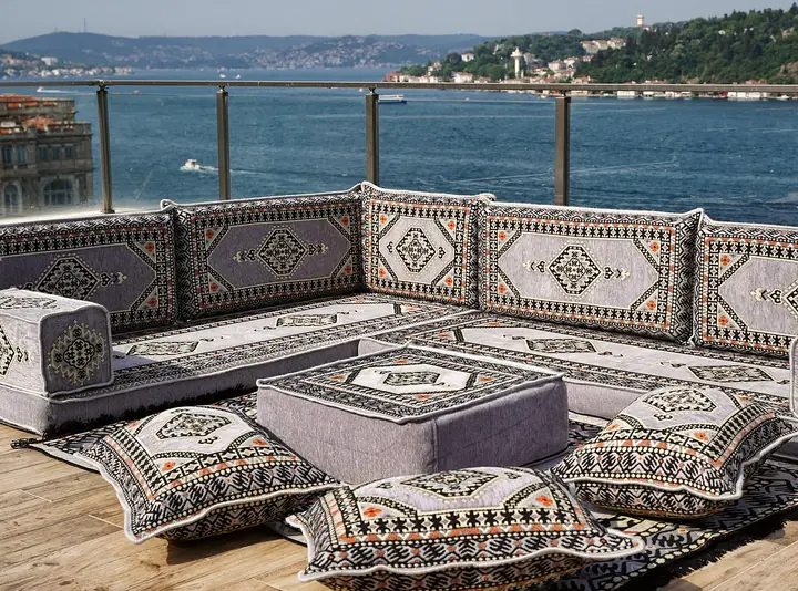 Light gray Saray L set with gray and cream medallion backrests, a gray ottoman and patterned floor pillows on the rug