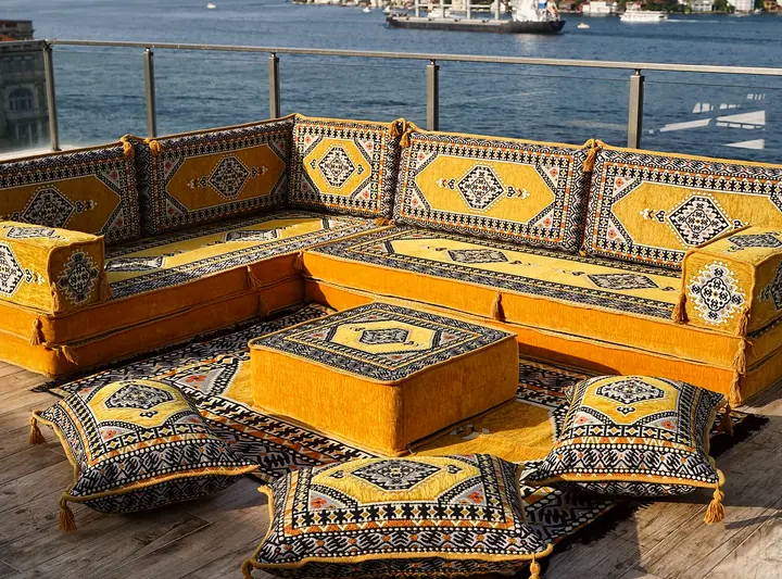 Mustard yellow medallion L set with thick seat cushions, a matching ottoman and floor pillows edged in a navy pattern