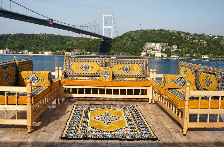 Mustard yellow cushions with black and gray medallion frames on wooden benches arranged on three sides of a rug
