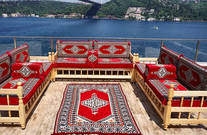 Red medallion back cushions framed in gray and black along three wooden benches, with bolsters at the open ends