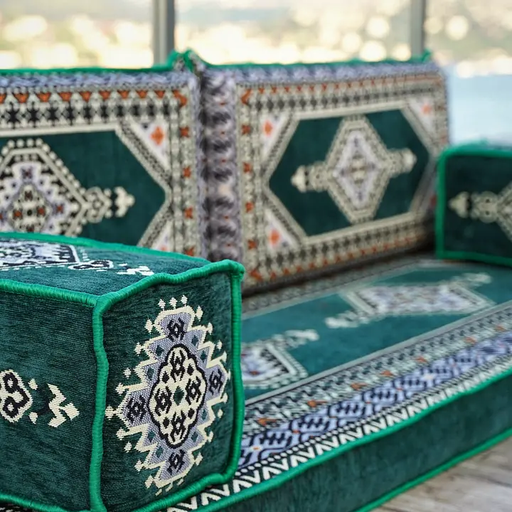 Close-up of a green medallion armrest beside the patterned back cushions of a straight floor seat