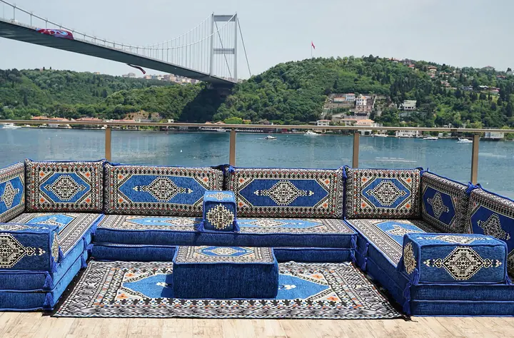 Blue Saray floor seating around an ottoman and rug, with black and cream medallions repeating on each backrest