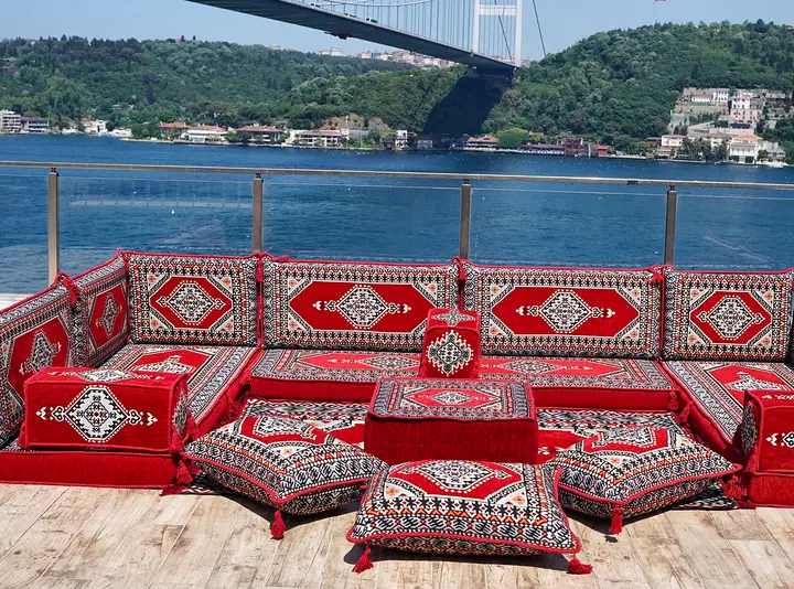 Red medallion seating on three walls with gray-framed motifs, a square ottoman and floor pillows grouped inside
