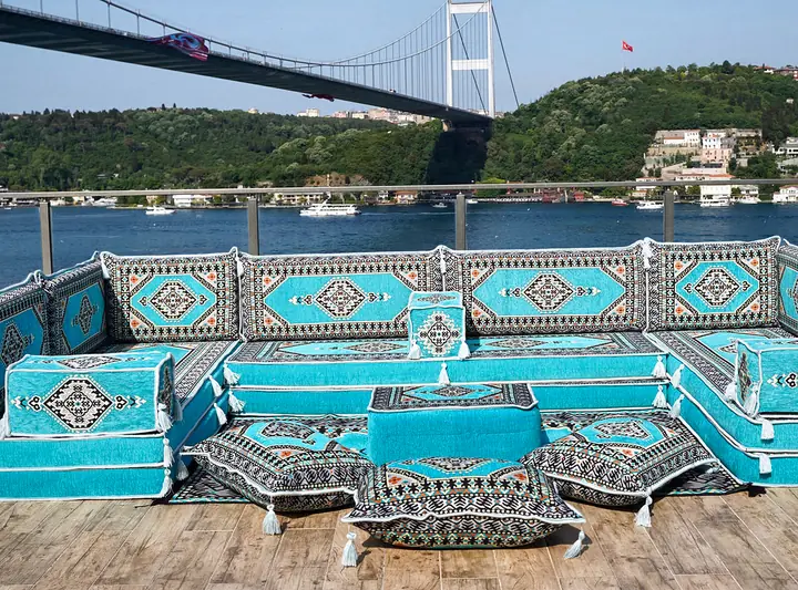 Turquoise medallion floor sofa wrapping three sides of an ottoman, with floor pillows set in the middle