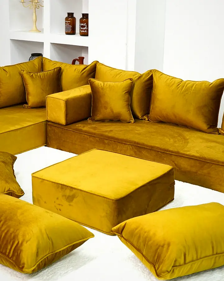 Thick gold velvet corner set with square backrests and block armrests, a gold ottoman and three floor pillows