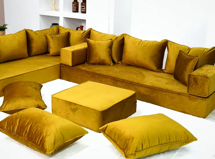 Thick gold velvet corner set with square backrests and block armrests, a gold ottoman and three floor pillows