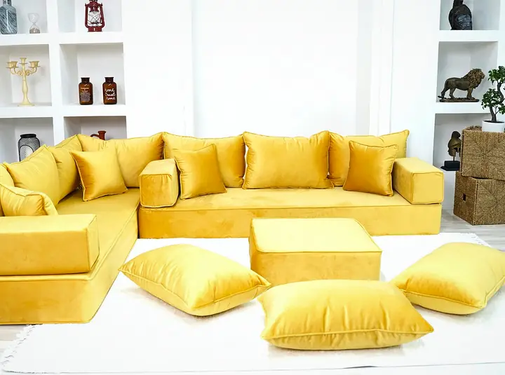Mustard yellow velvet corner floor seating with square backrests, a mustard ottoman and three floor pillows in front