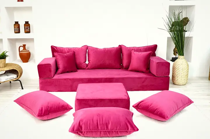 Pink velvet floor sofa set with square backrests and throw pillows, a pink ottoman and three floor cushions in front
