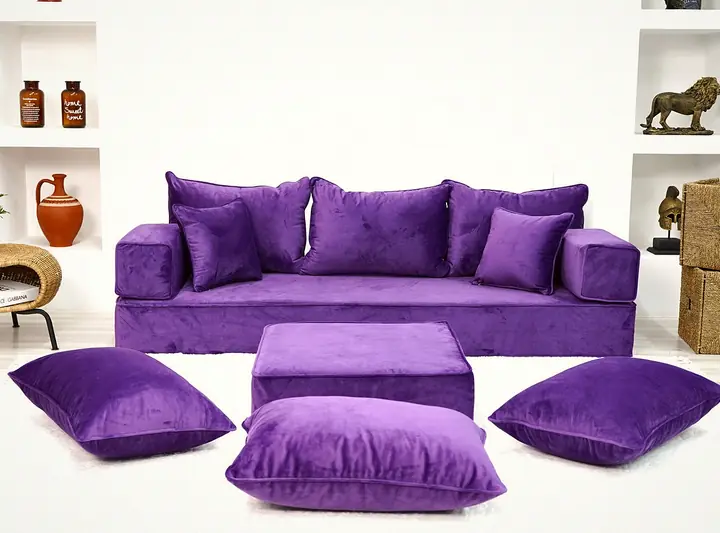 Purple velvet one-wall floor sofa with square backrests, a purple ottoman and three floor cushions, seen from the front
