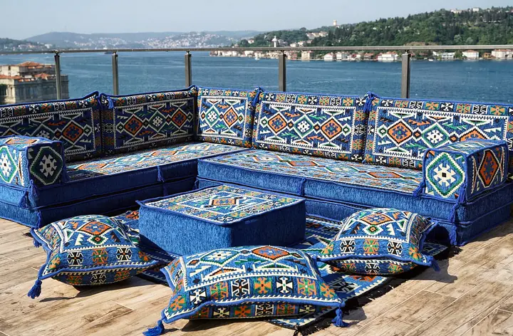 Royal blue kilim corner set with thick seat cushions, an ottoman and floor pillows in the open corner