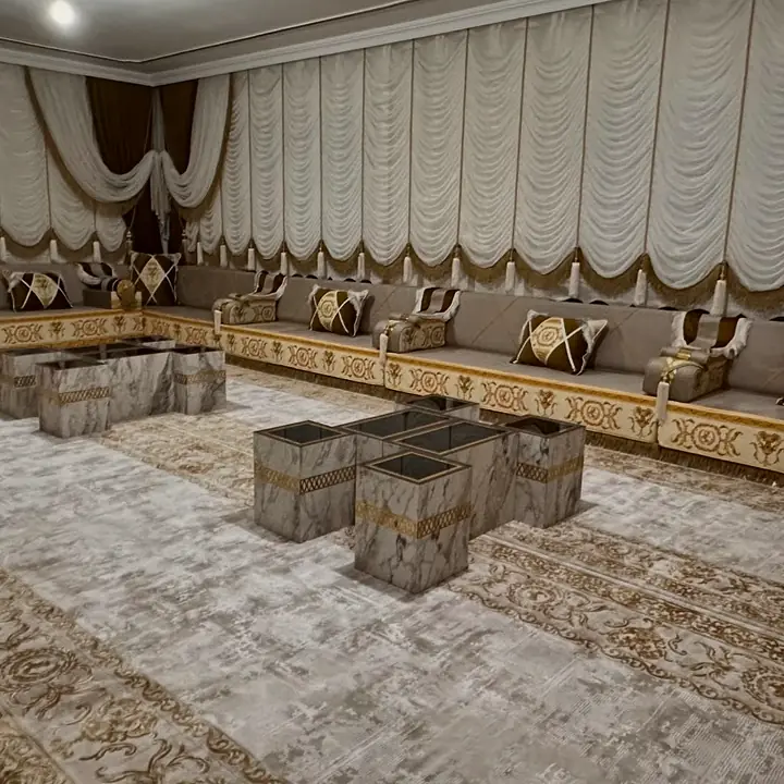 Wide view of taupe seating with amber-gold baroque print along the base and gold fringe below it, under festoon blinds
