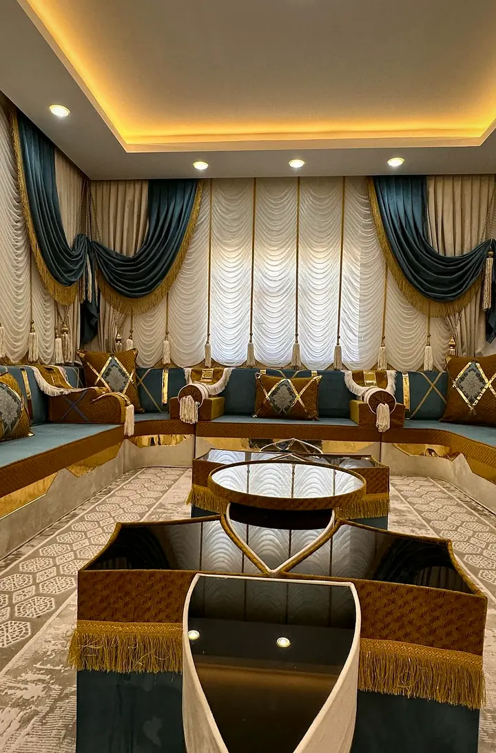 U-shaped majlis in teal and mustard velvet with gold trim, two fringed star tables in the middle and white swag curtains