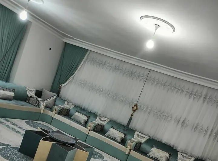 Teal and sage majlis seating under white embroidered sheers, with a star-shaped teal and cream table on a cream medallion rug