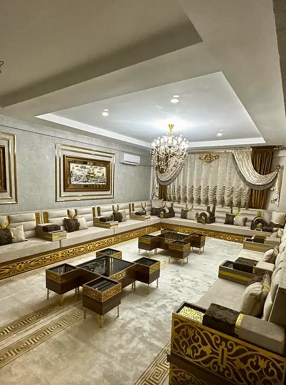 Cream and gold majlis with plain low backrests and framed gold wall art hung just above the seating line