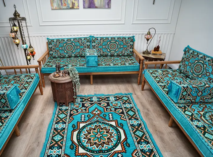 Turquoise kilim cushions on three pine benches arranged in a U around a medallion rug, with mosaic lamps and a white paneled wall